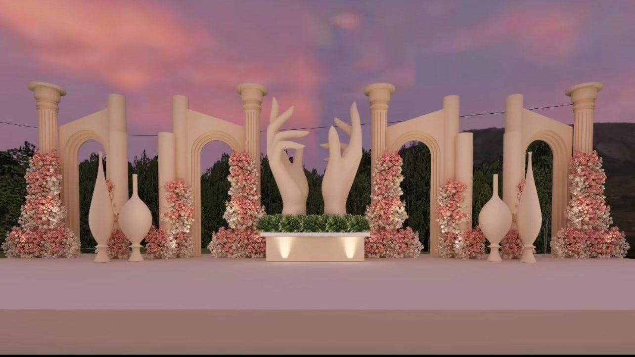 Pastel stage with classical columns, sculpted hand motifs and blush floral pillars by RAW Group